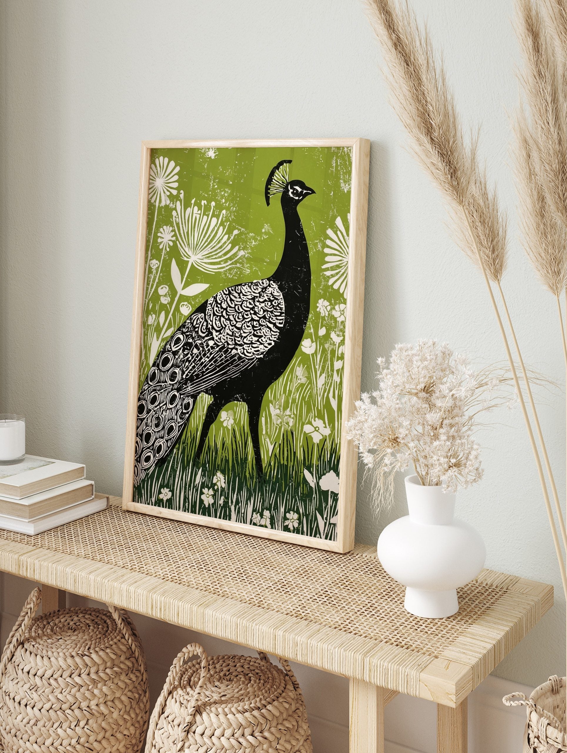 Black peacock linocut illustration with white patterns, green botanical background, and white, in an alternate framed mockup