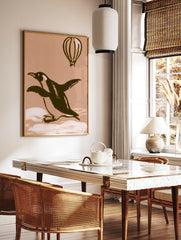 Illustrative penguin and hot air balloon art print on a warm beige background, in a styled room mockup
