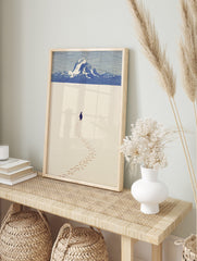 Minimalist illustrative print of a penguin walking in snow, leaving footprints, with blue, in an alternate framed mockup
