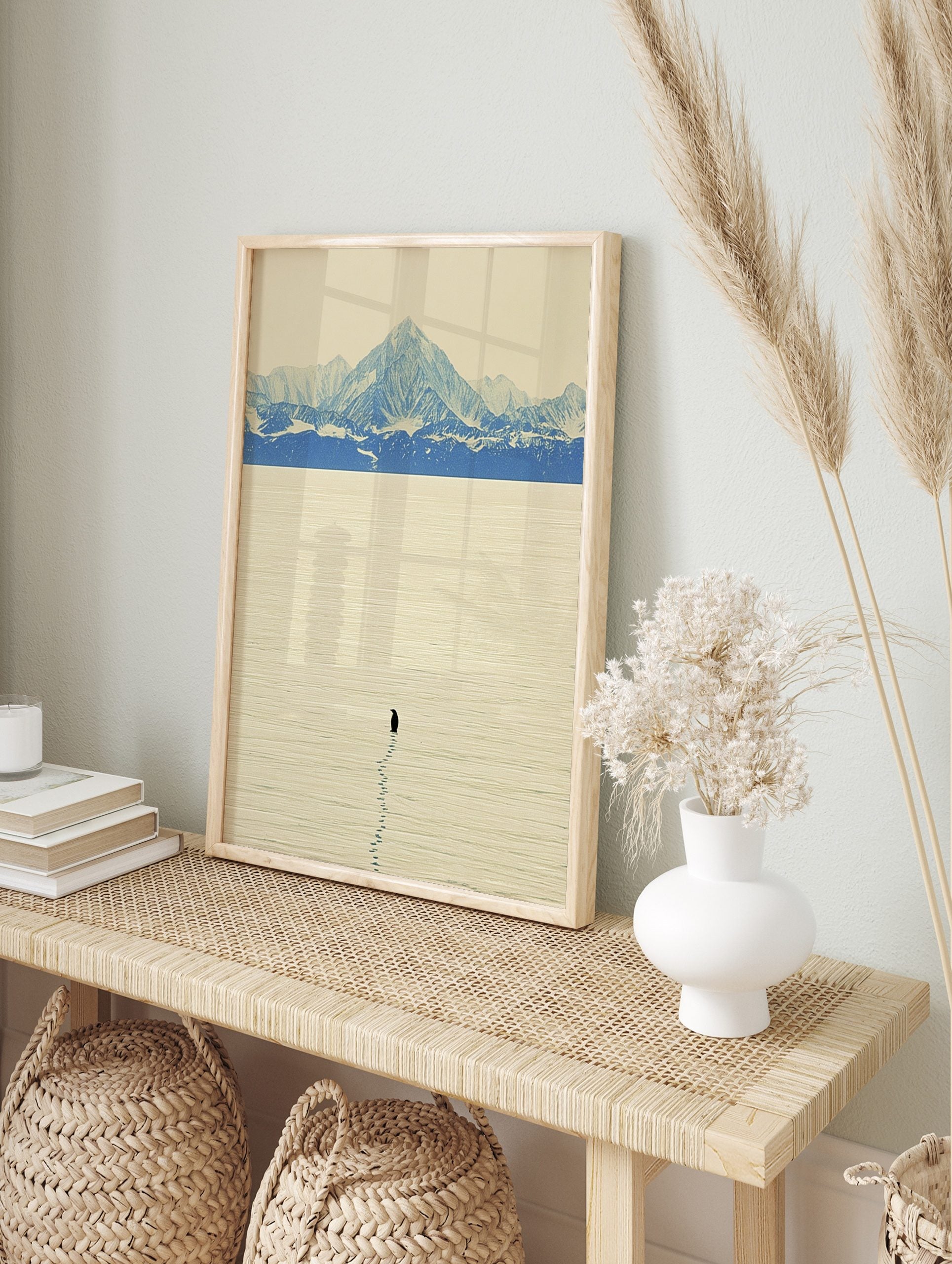 Minimalist art print of a lone black penguin on textured ice with blue and white snow, in an alternate framed mockup