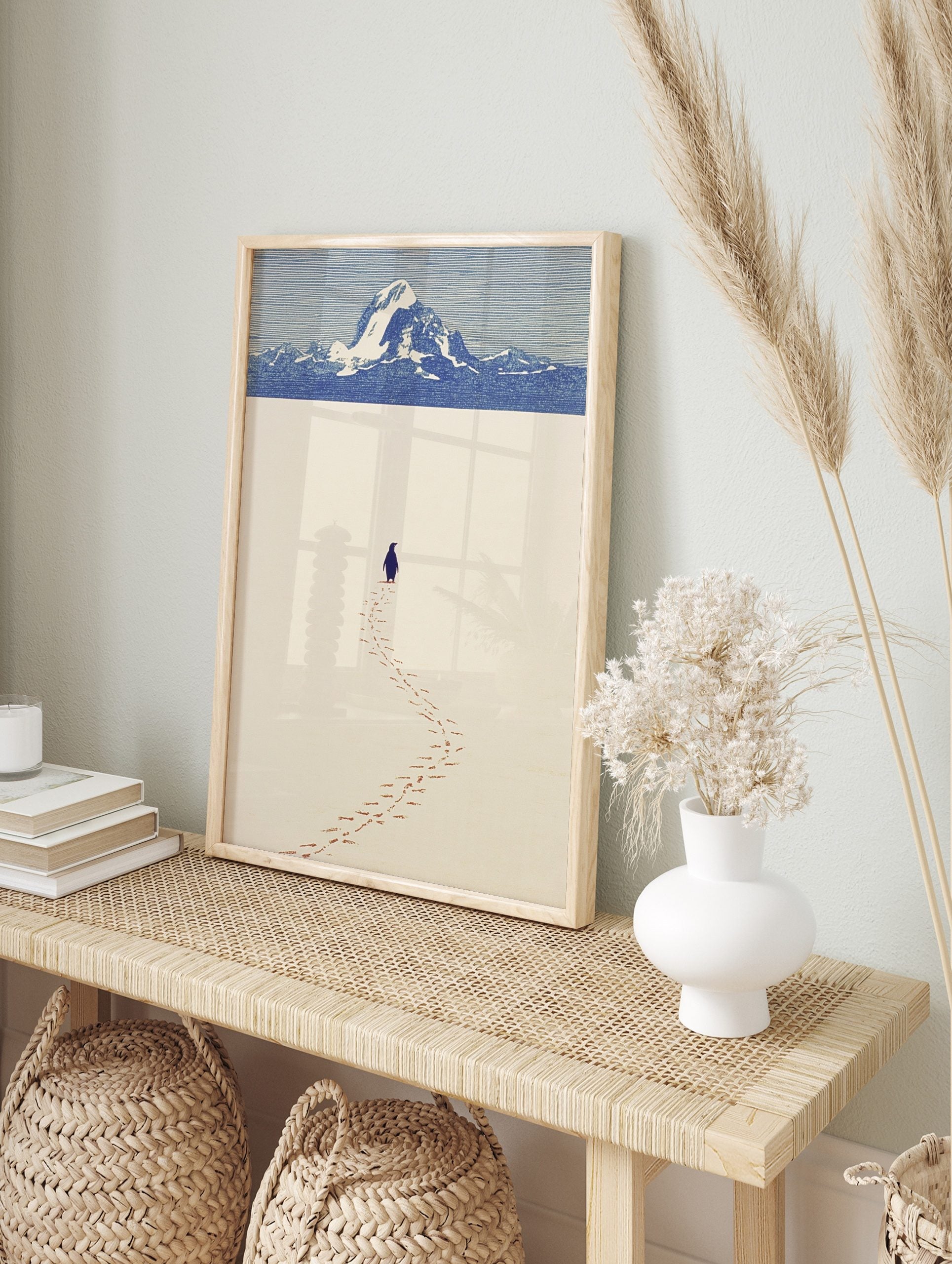 Minimalist art print of a penguin walking on a vast snow plain towards distant blue mountains, in an alternate framed mockup