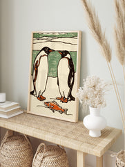 Illustrative print of two black and white penguins facing each other, with an orange fish on, in an alternate framed mockup