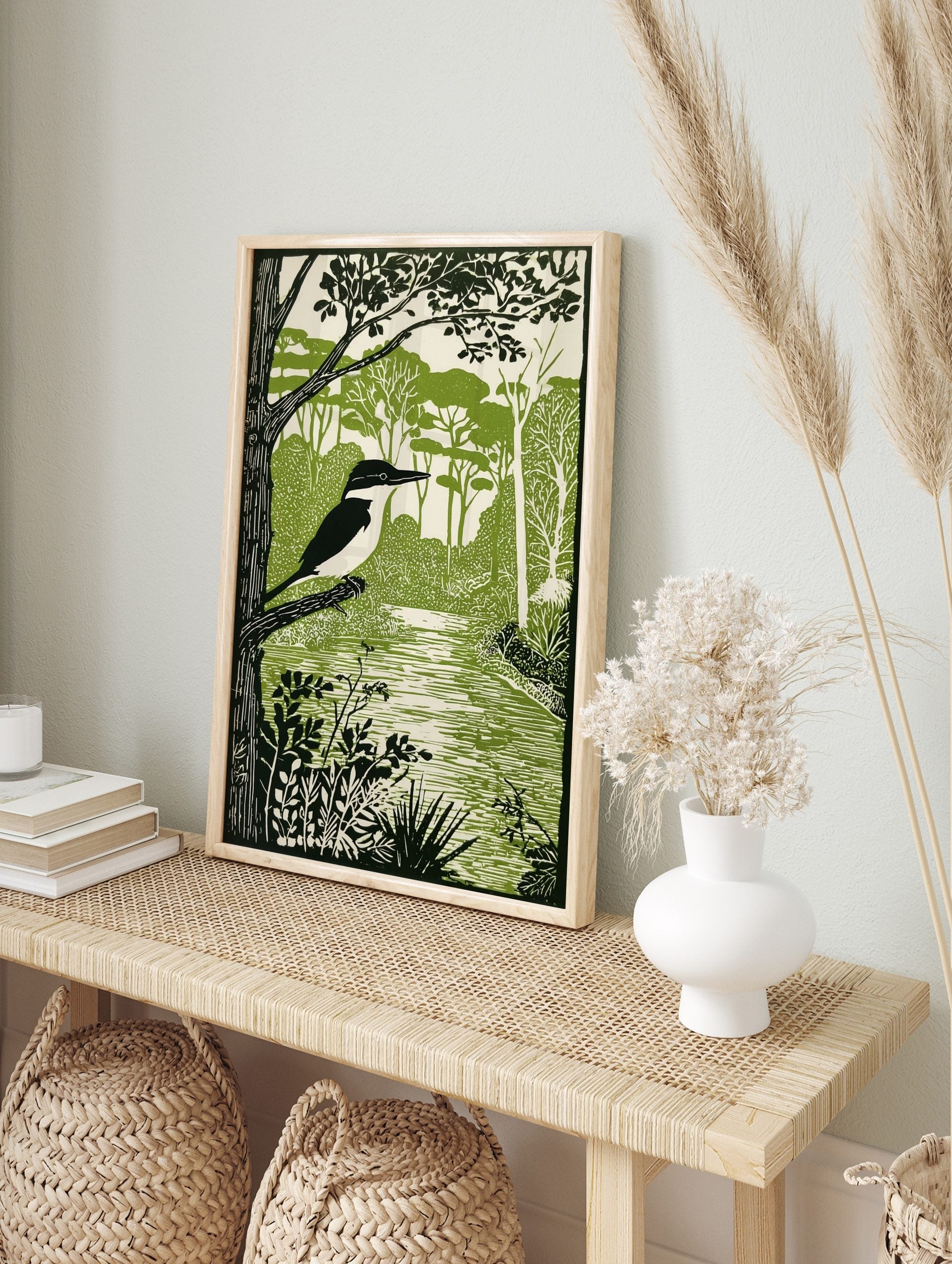 Illustrative green and white print of a pied kingfisher on a branch by a river with dense, in an alternate framed mockup