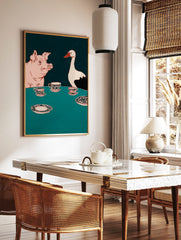 Illustrative wall art of a pink pig and white goose at a teal table with ornate teacups, in a styled room mockup