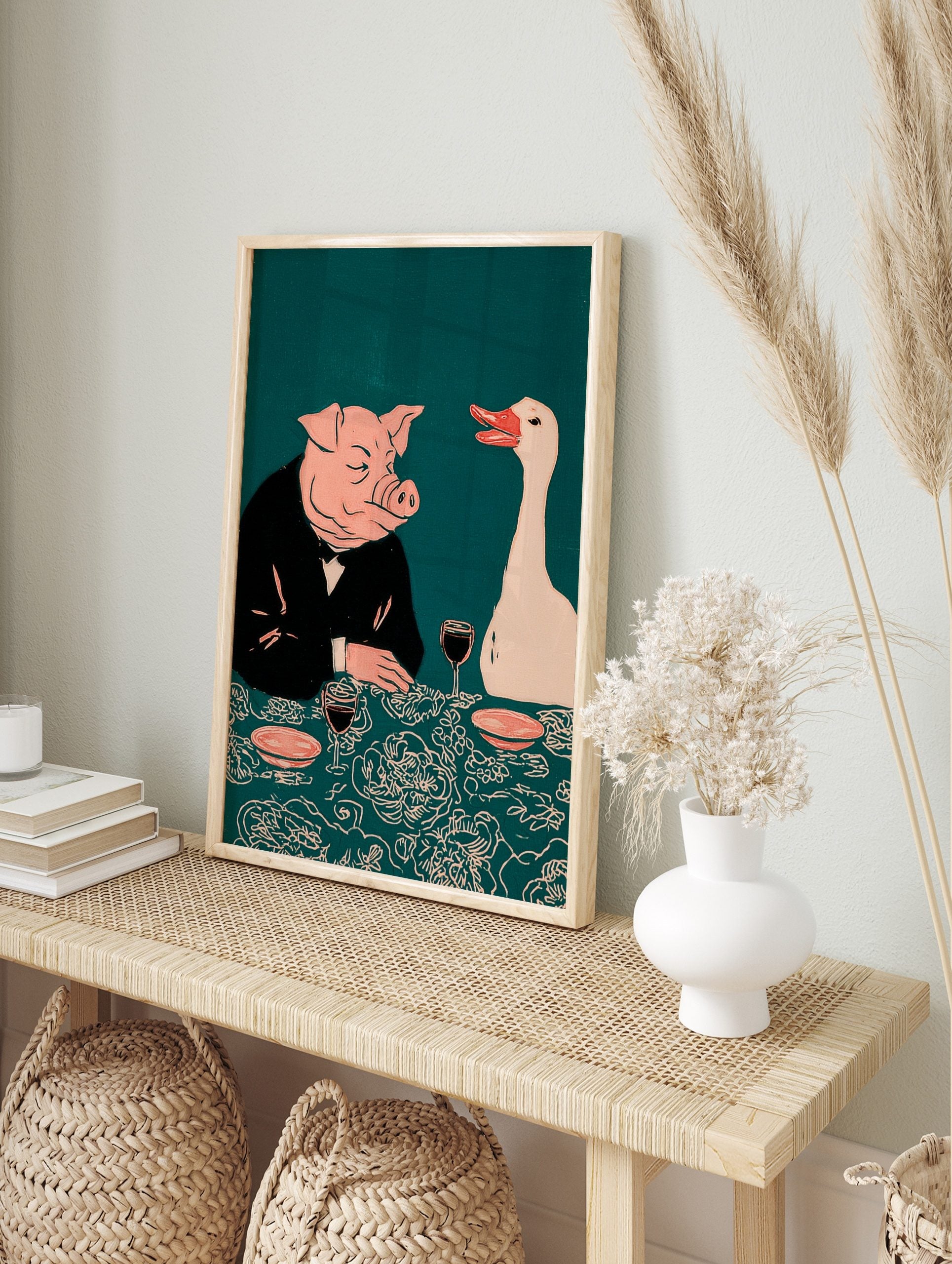 Illustrative print of a pig in a suit and a white goose at a dinner table with wine, on a, in an alternate framed mockup
