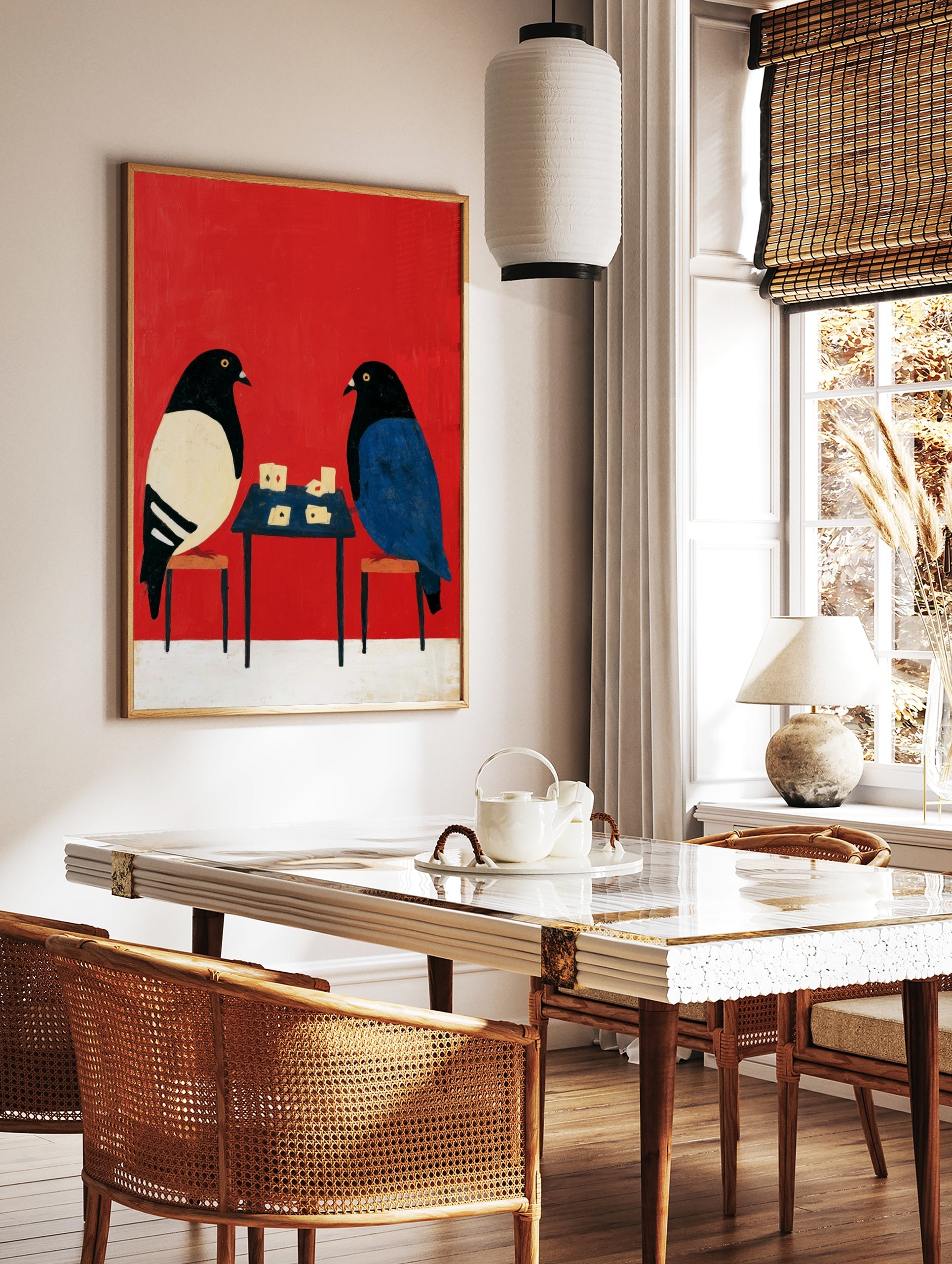 Stylised illustration of two pigeons playing cards on a small table against a solid vibrant red, in a styled room mockup