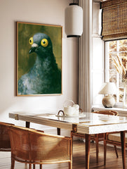 Close-up painting of a pigeon with large yellow eyes and textured dark feathers against a muted, in a styled room mockup