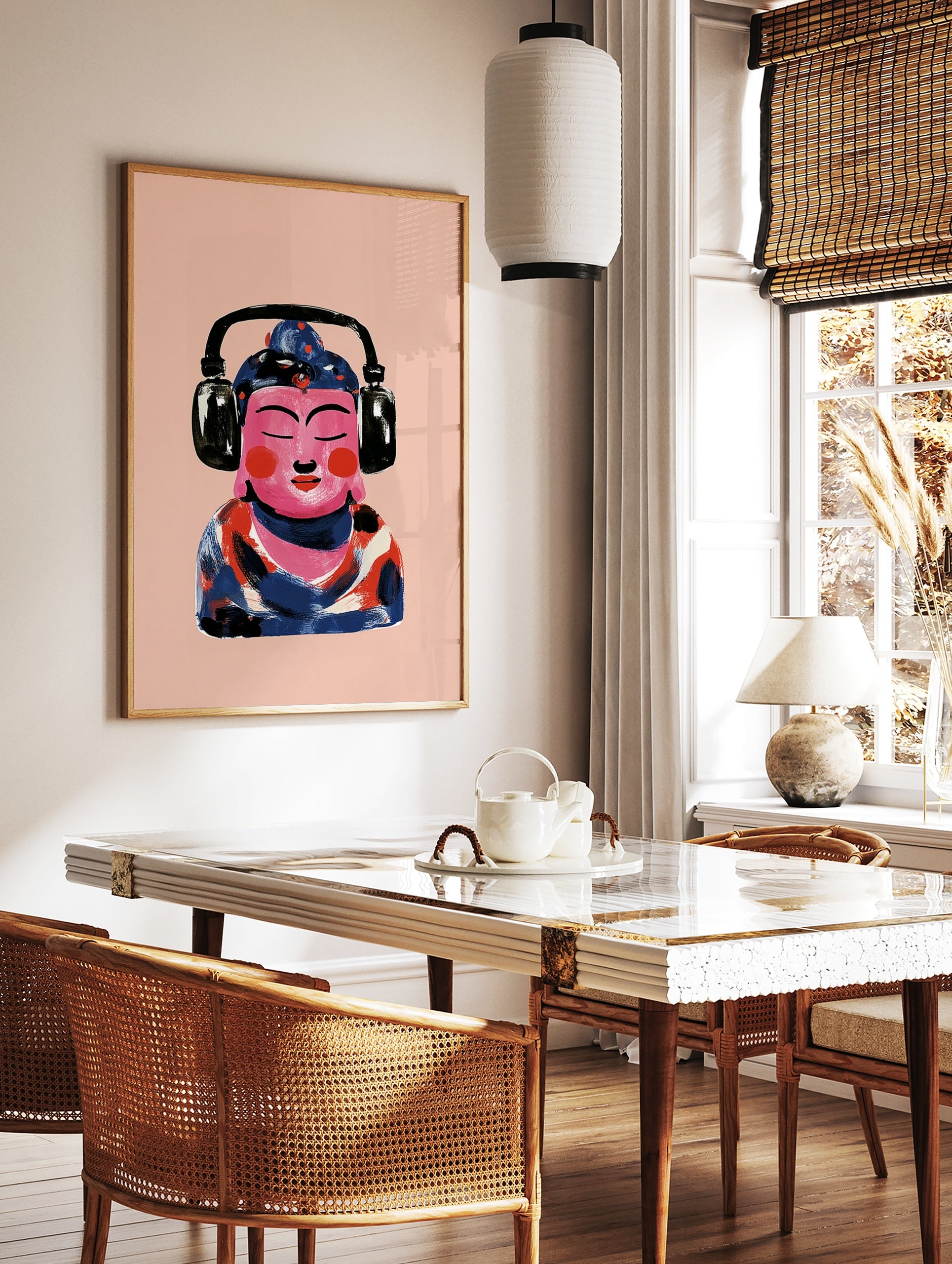 Illustrative print of a pink Buddha figure wearing black headphones against a light pink background, in a styled room mockup