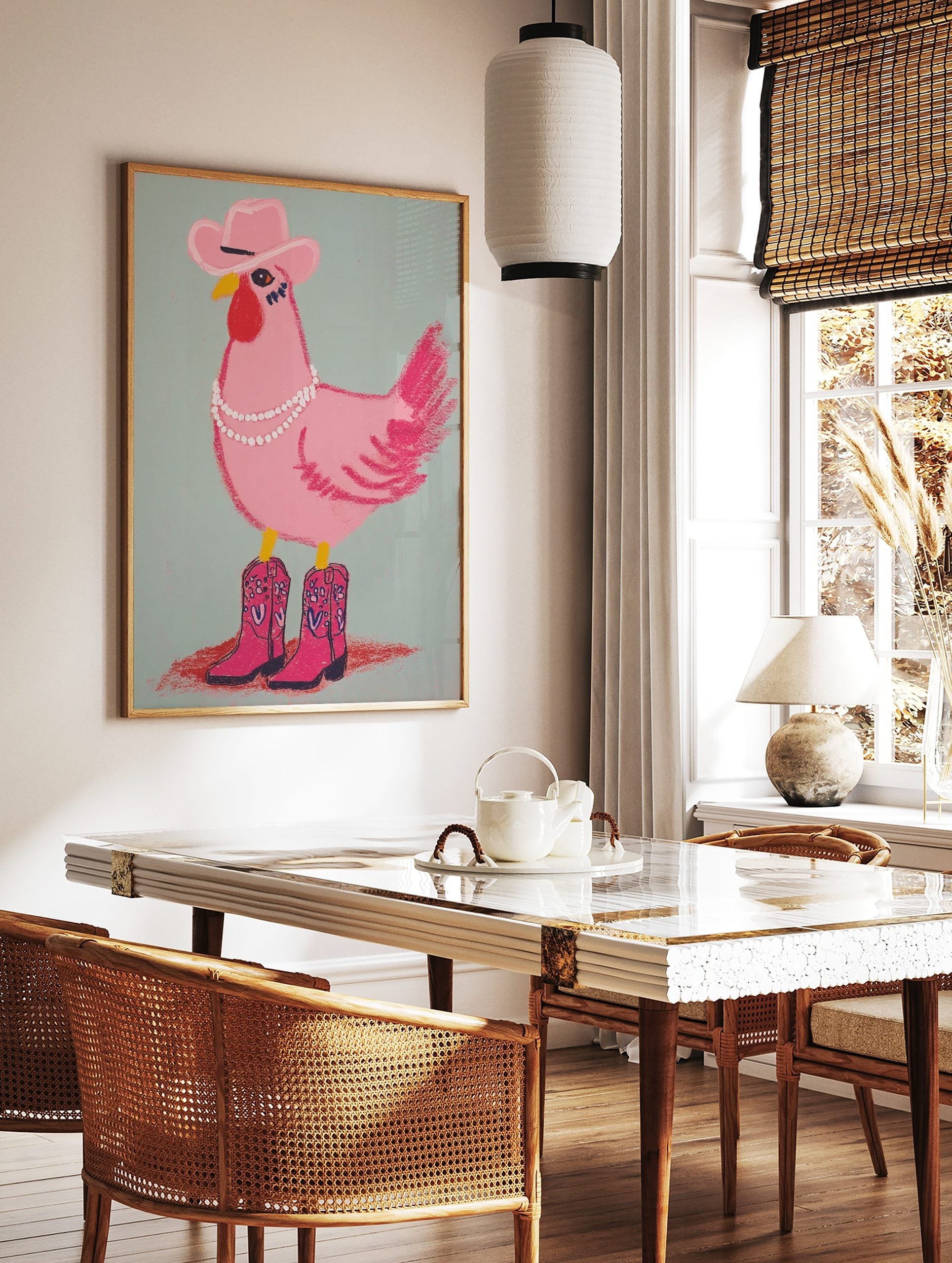 Illustrative pink chicken wearing a cowboy hat, pearl necklace, and pink cowboy boots on a light, in a styled room mockup