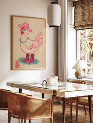 Illustrative print of a pink cowgirl chicken wearing a cowboy hat, beaded necklace, and boots on a, in a styled room mockup