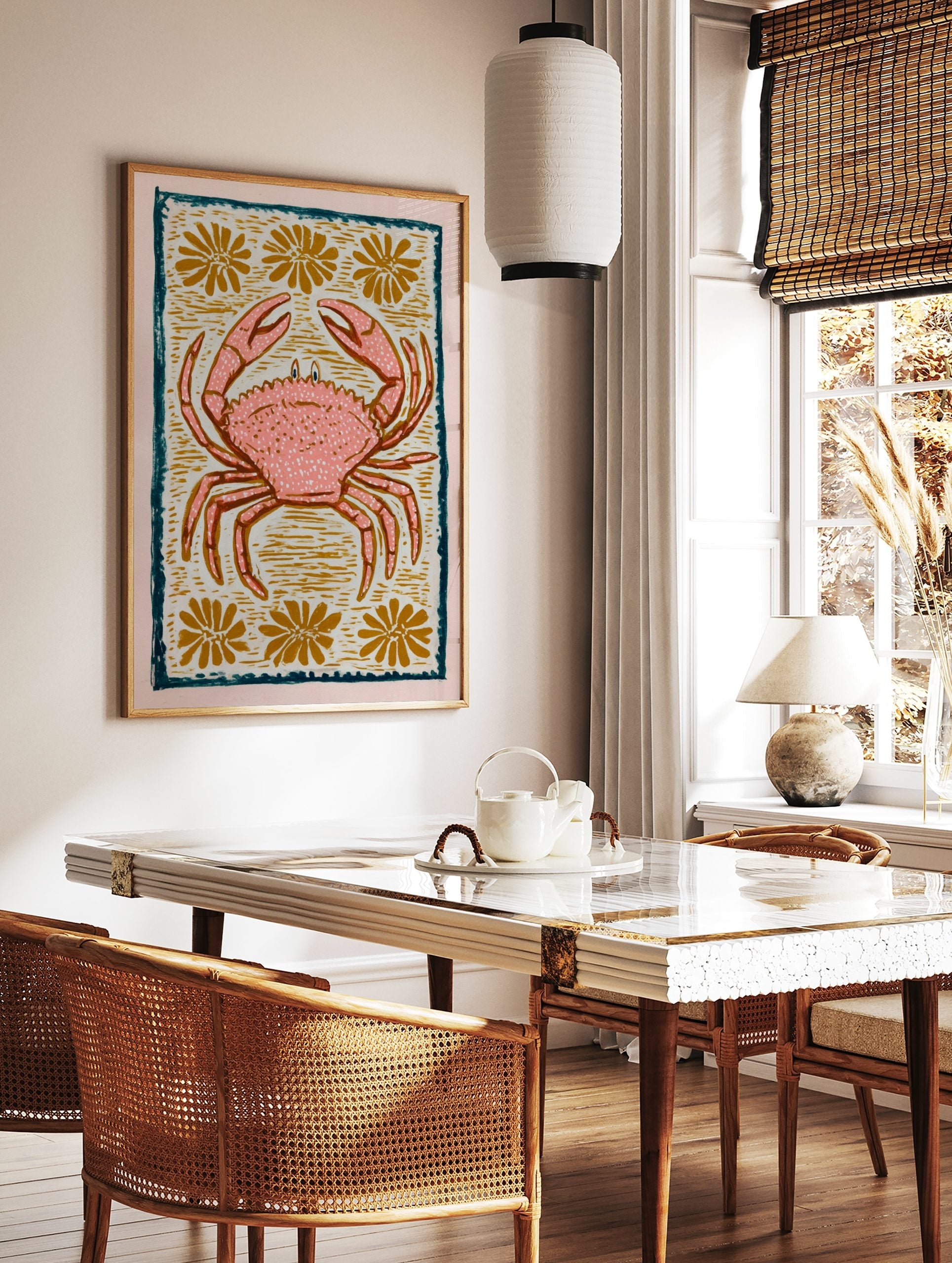 Pink crab illustration with white speckles, golden flowers, and a dark teal border on a light, in a styled room mockup