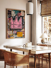 Bold pink crown with black outlines on a layered, abstract background of black, teal, and yellow, in a styled room mockup