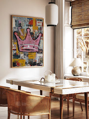 Pink crown with black outlines on a distressed, multi-colour street art background with text, in a styled room mockup