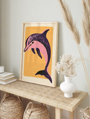 Stylized pink dolphin illustration on a textured orange background, illustrative sea animal, in an alternate framed mockup
