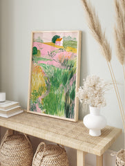 Illustrative landscape art print with pink fields, green bushes, yellow grass, and a small, in an alternate framed mockup