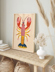 Illustrative pink lobster print with dotted red claws, yellow legs, and navy tail on a beige, in an alternate framed mockup