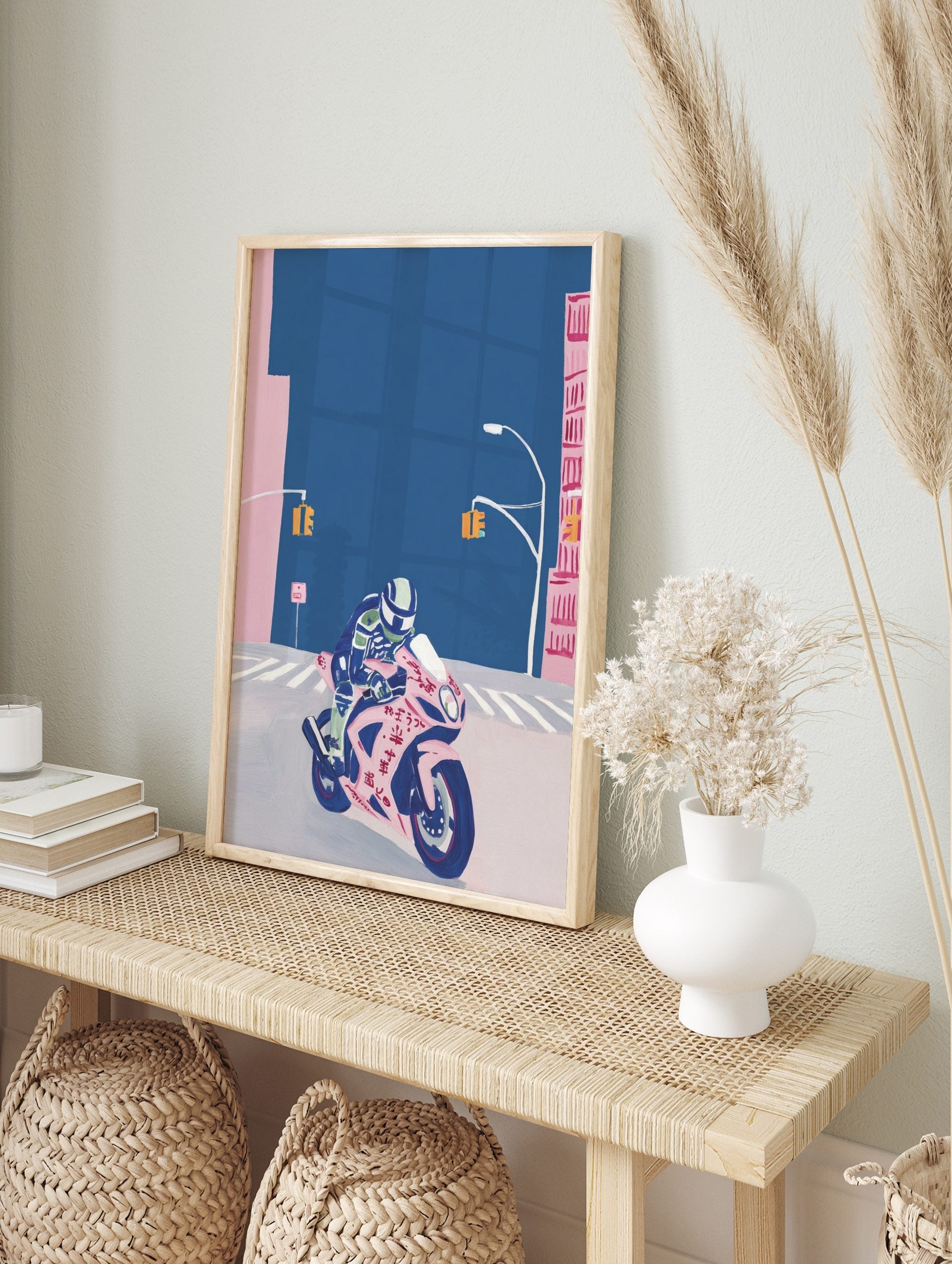 Illustrative print of a rider on a pink sports motorbike with Japanese text, on a deep blue, in an alternate framed mockup