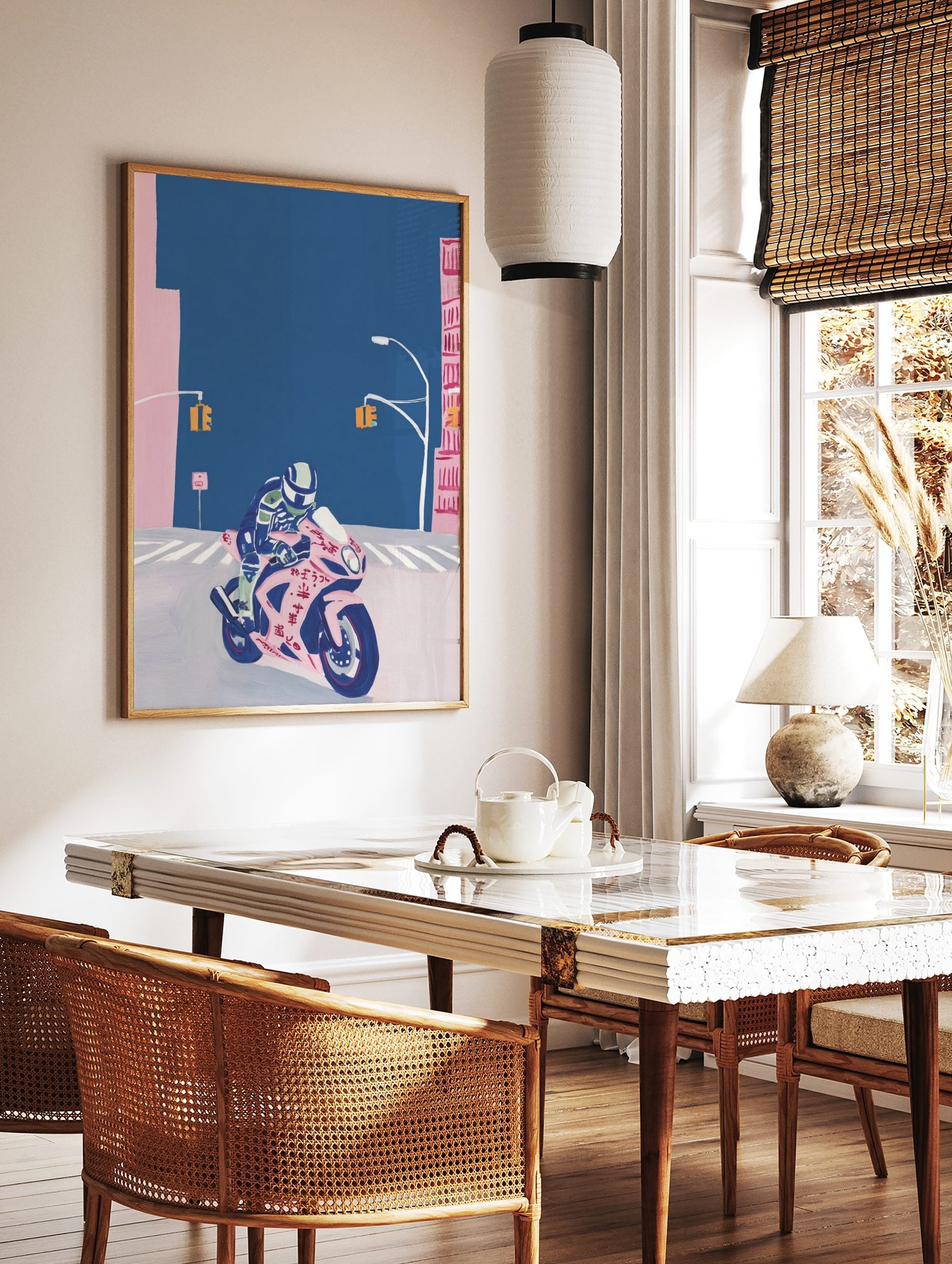 Illustrative print of a rider on a pink sports motorbike with Japanese text, on a deep blue street, in a styled room mockup