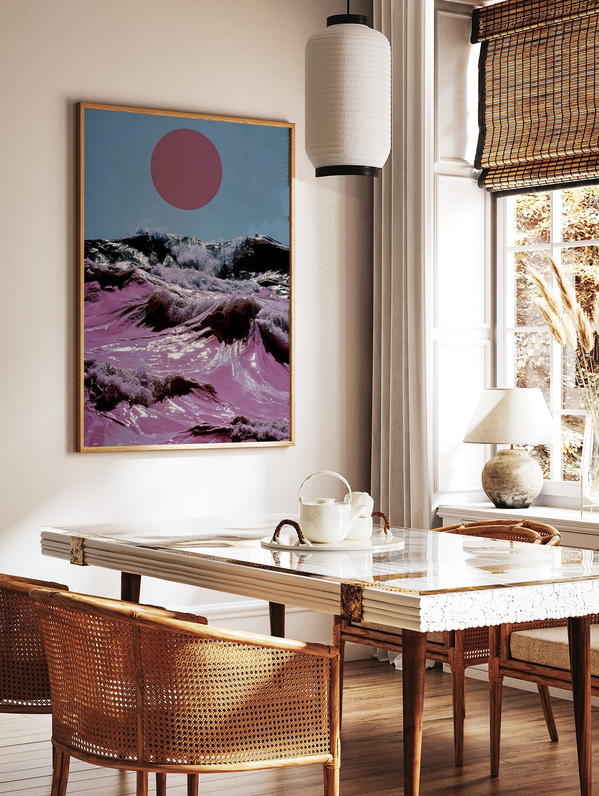Surreal art print of pink ocean waves crashing with white foam under a large red sun in a blue sky, in a styled room mockup