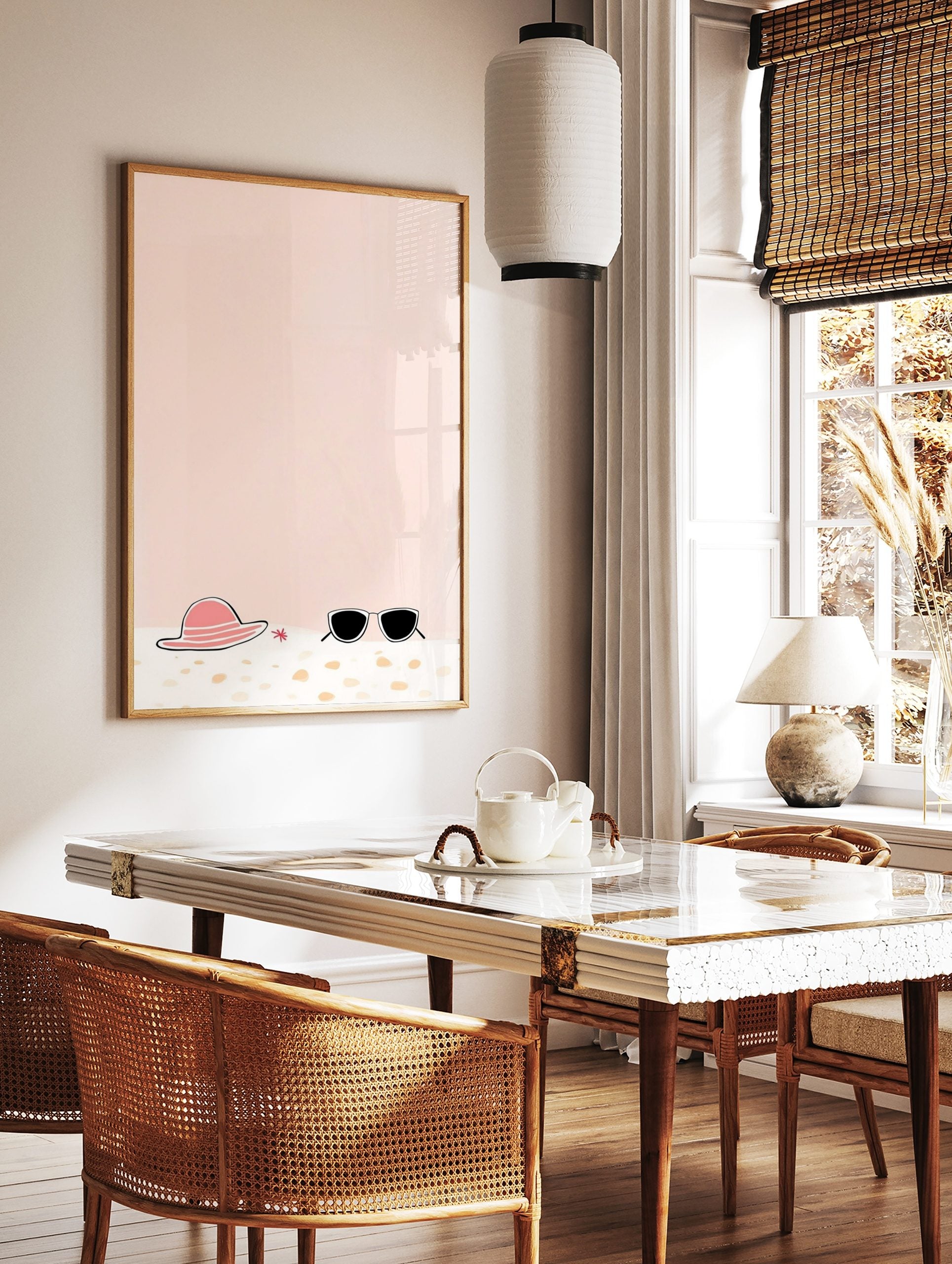 Illustrative print of a pink sun hat, black sunglasses, and red starfish on sand with a peach, in a styled room mockup