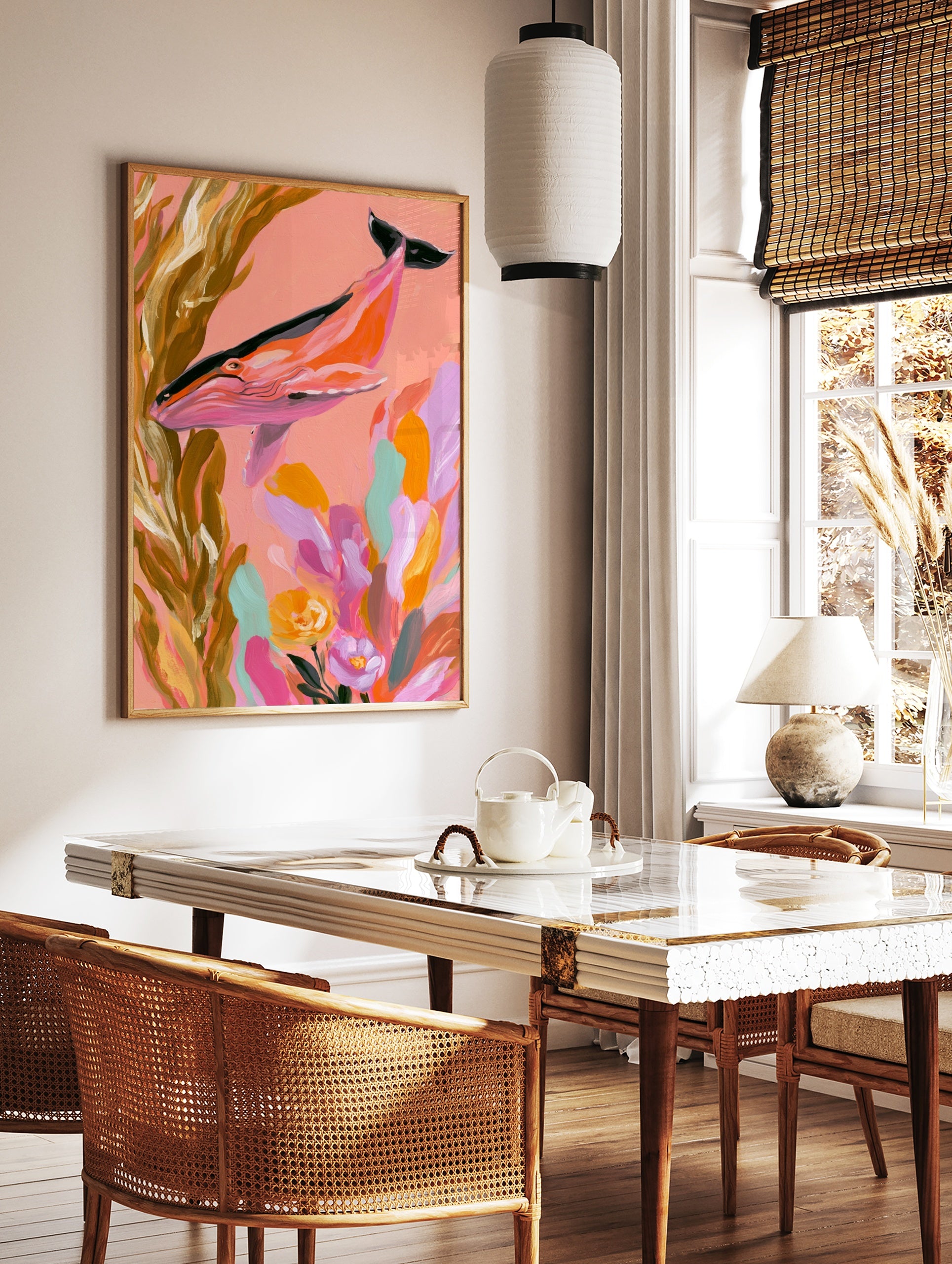 Illustrative pink whale swimming through golden kelp and colourful flowers on a coral background, in a styled room mockup
