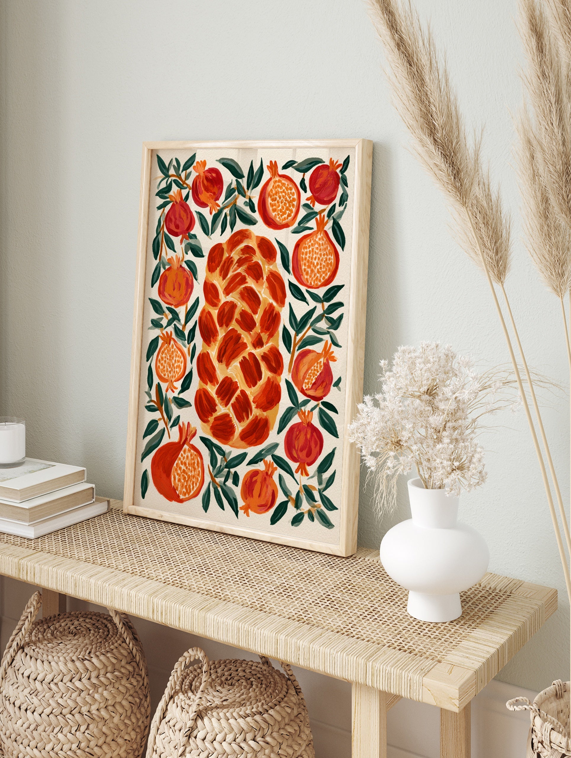 Illustrative wall art print of a central braided challah bread surrounded by red pomegranates, in an alternate framed mockup