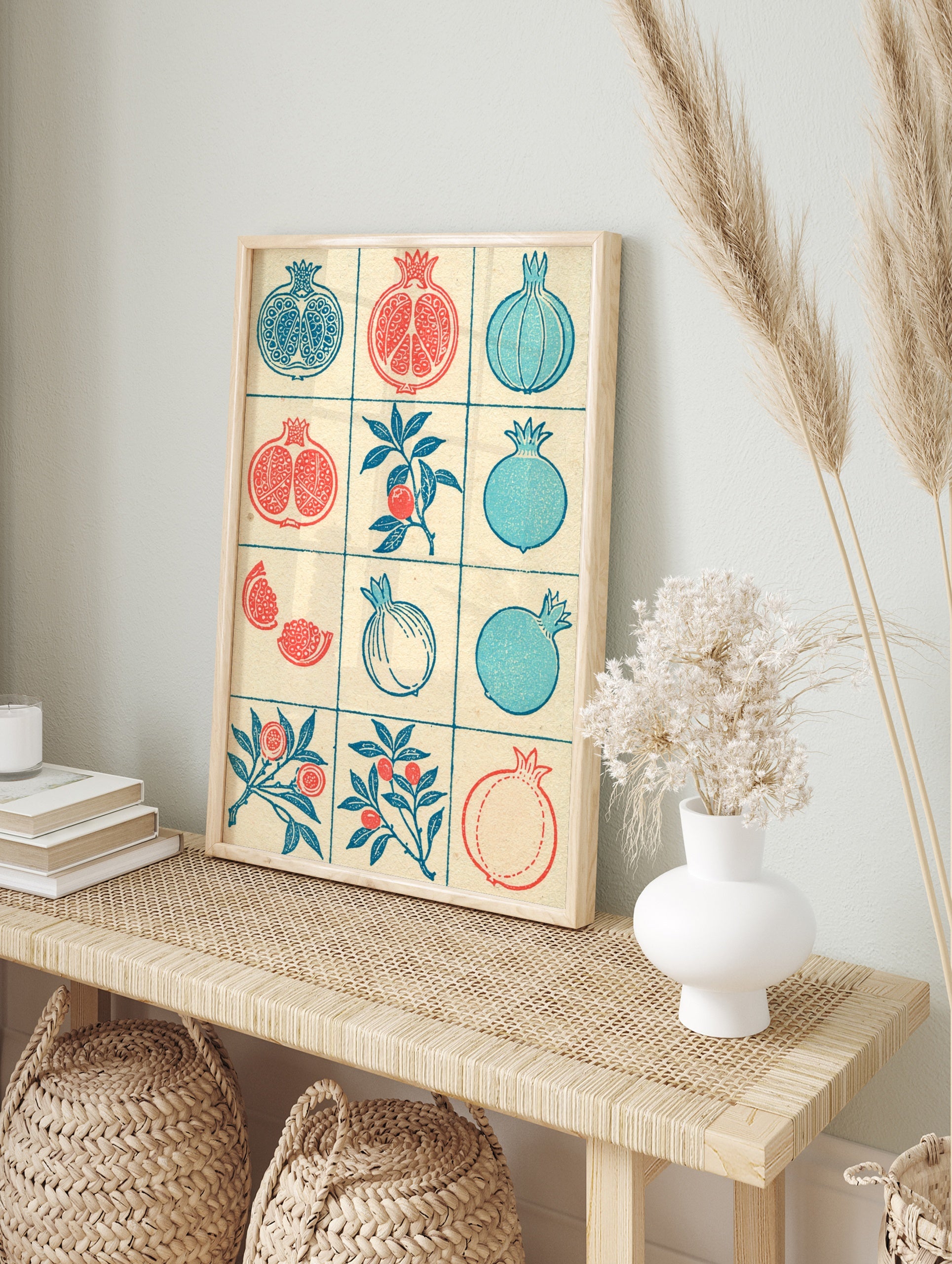 Grid of illustrative pomegranate fruit and branch designs in red and blue on a textured cream, in an alternate framed mockup