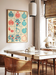 Grid of illustrative pomegranate fruit and branch designs in red and blue on a textured cream, in a styled room mockup