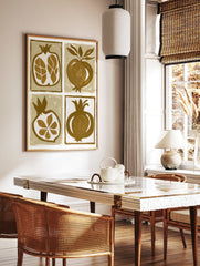 Four illustrative pomegranate prints in brown and tan, featuring whole fruit and cross-sections in, in a styled room mockup