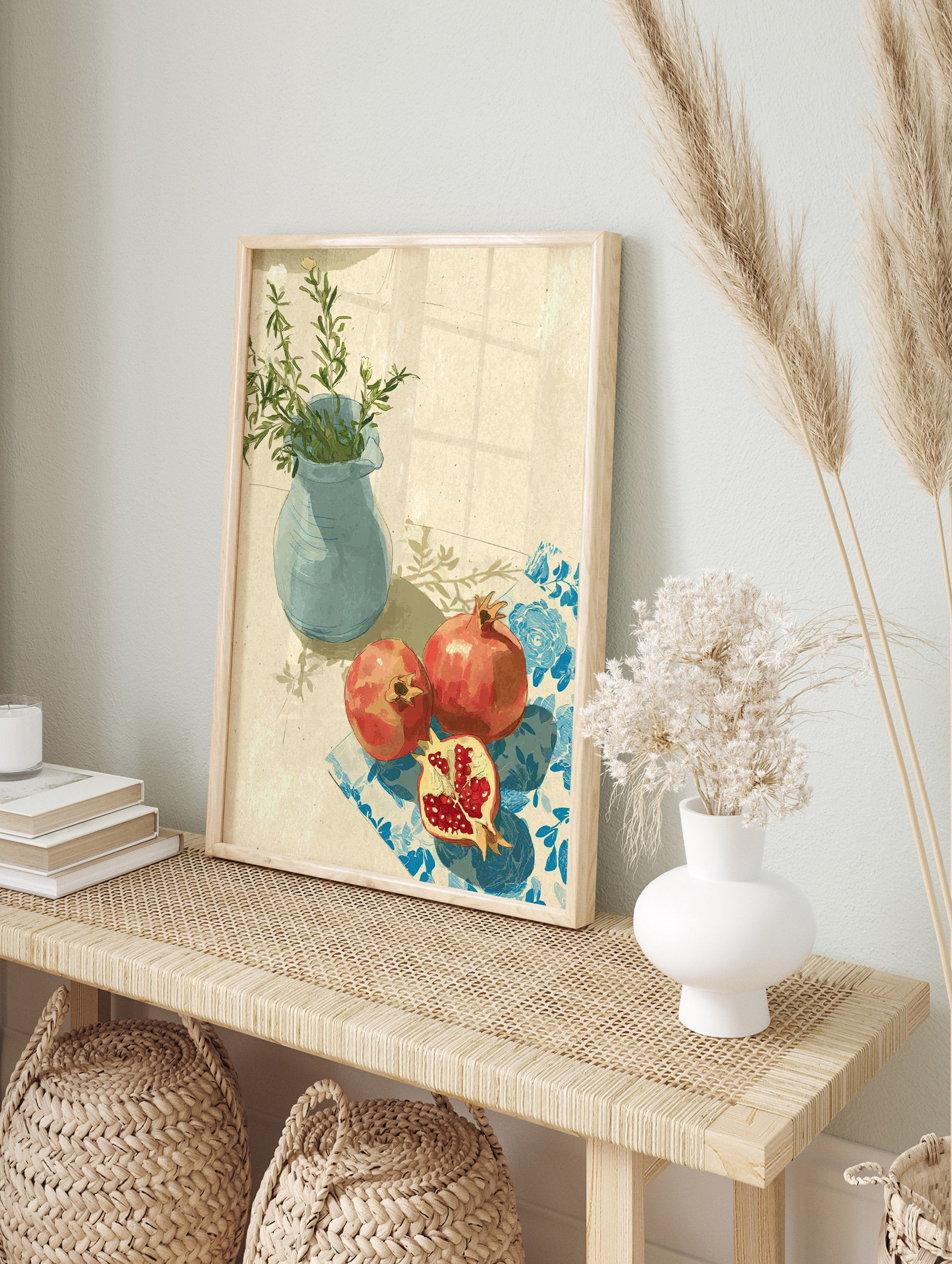 Pomegranate wall art with two red pomegranates, one cut, on a blue patterned cloth next to a blue vase with green leaves. - Image 3