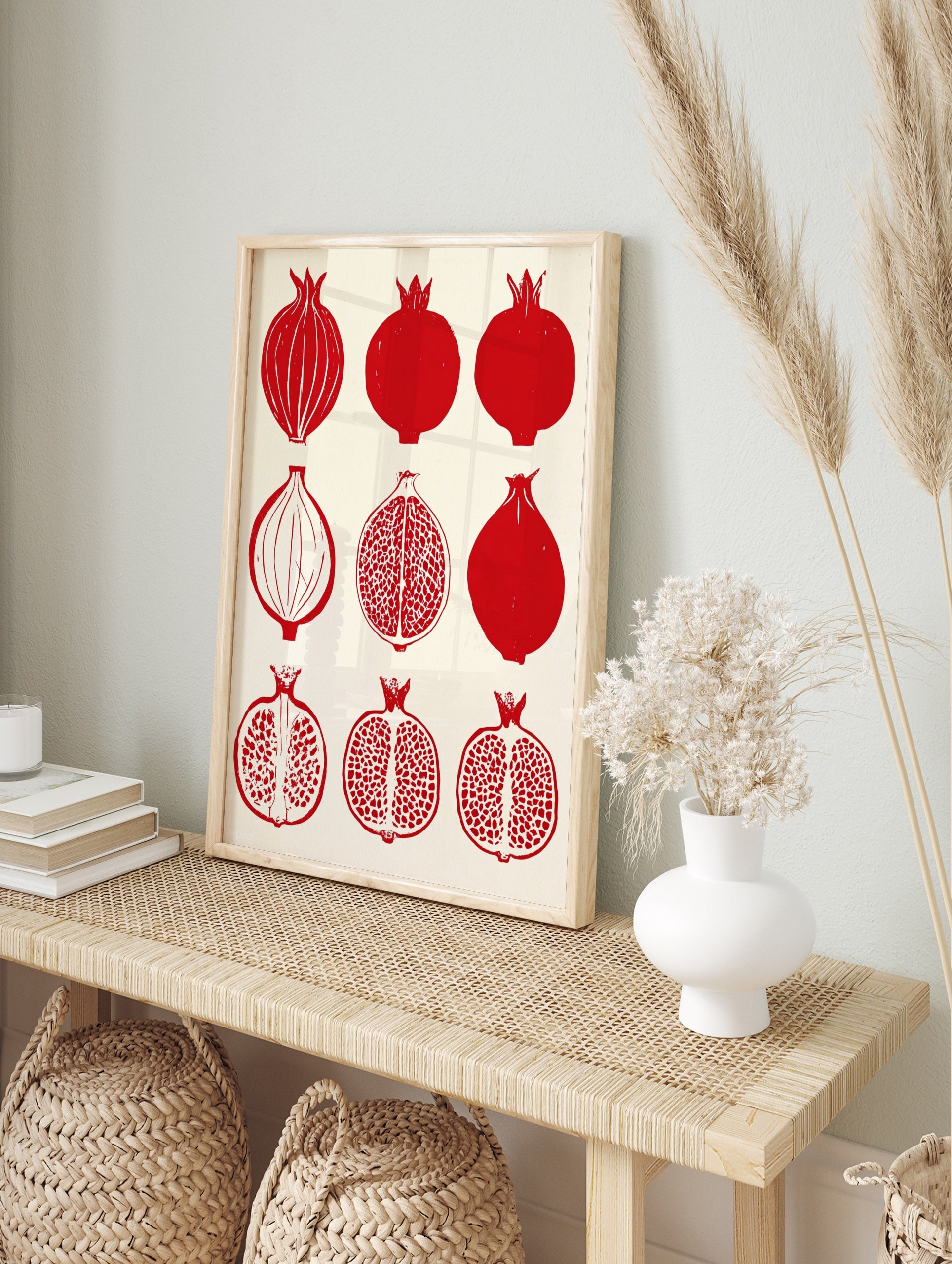 Grid of nine illustrative red pomegranate fruits, both whole and halved, on a cream background, in an alternate framed mockup