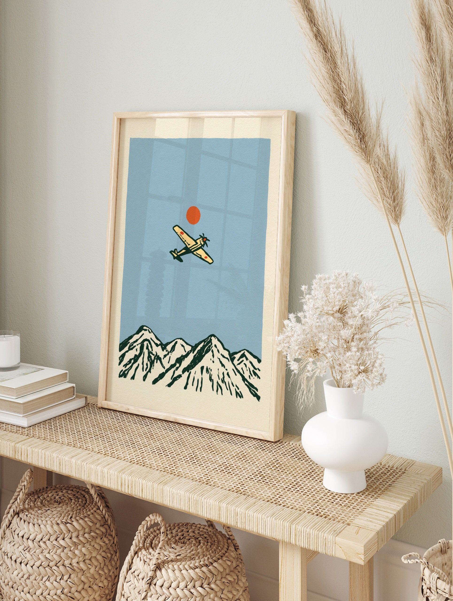 Vintage style illustration of a propeller aircraft flying over a mountain range with a red sun, in an alternate framed mockup