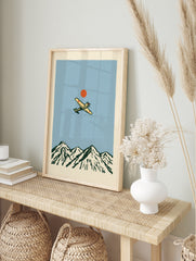 Vintage style illustration of a propeller aircraft flying over a mountain range with a red sun, in an alternate framed mockup