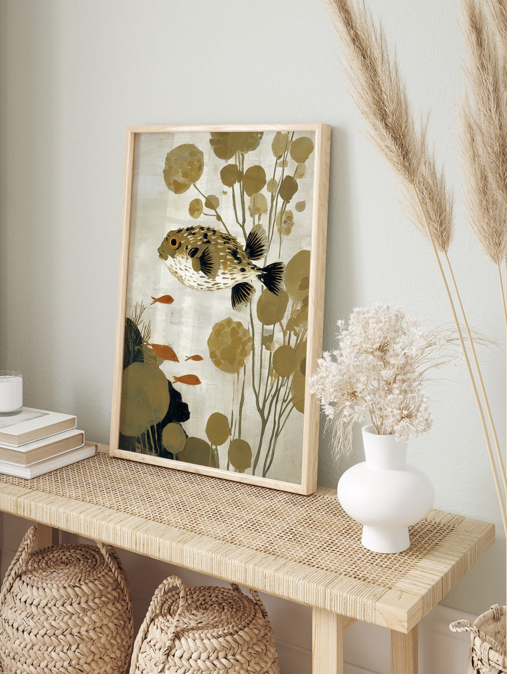Illustrative puffer fish wall art with spiky body, orange eye, olive plants, and small orange, in an alternate framed mockup