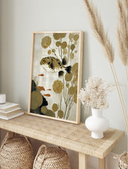 Illustrative puffer fish wall art with spiky body, orange eye, olive plants, and small orange, in an alternate framed mockup