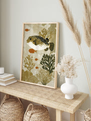 Illustrative art print of a spotted pufferfish with orange fish and coral in earthy tones, in an alternate framed mockup