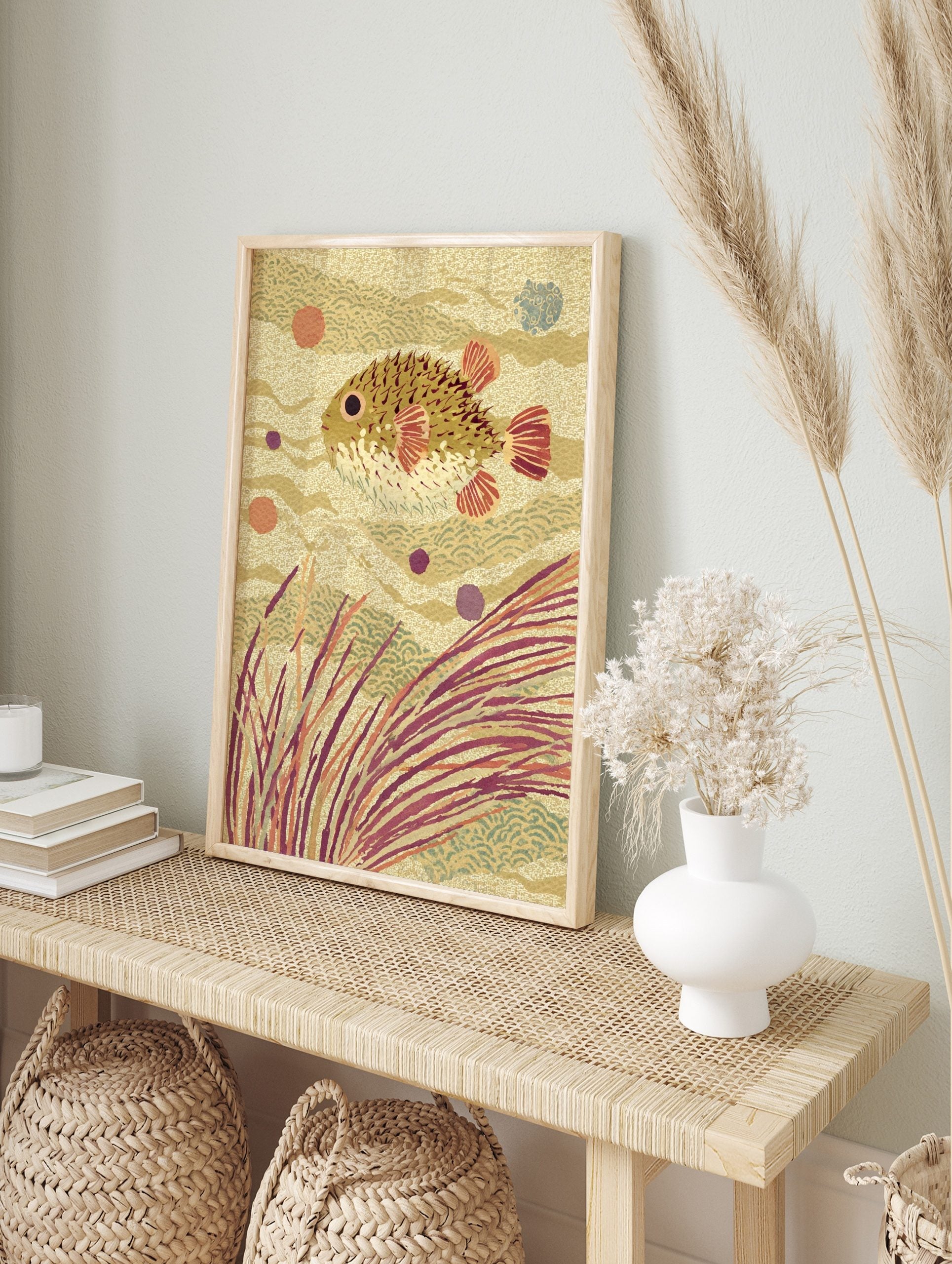 Illustrative pufferfish swimming among seaweed and wavy patterns in warm earth tones, in an alternate framed mockup