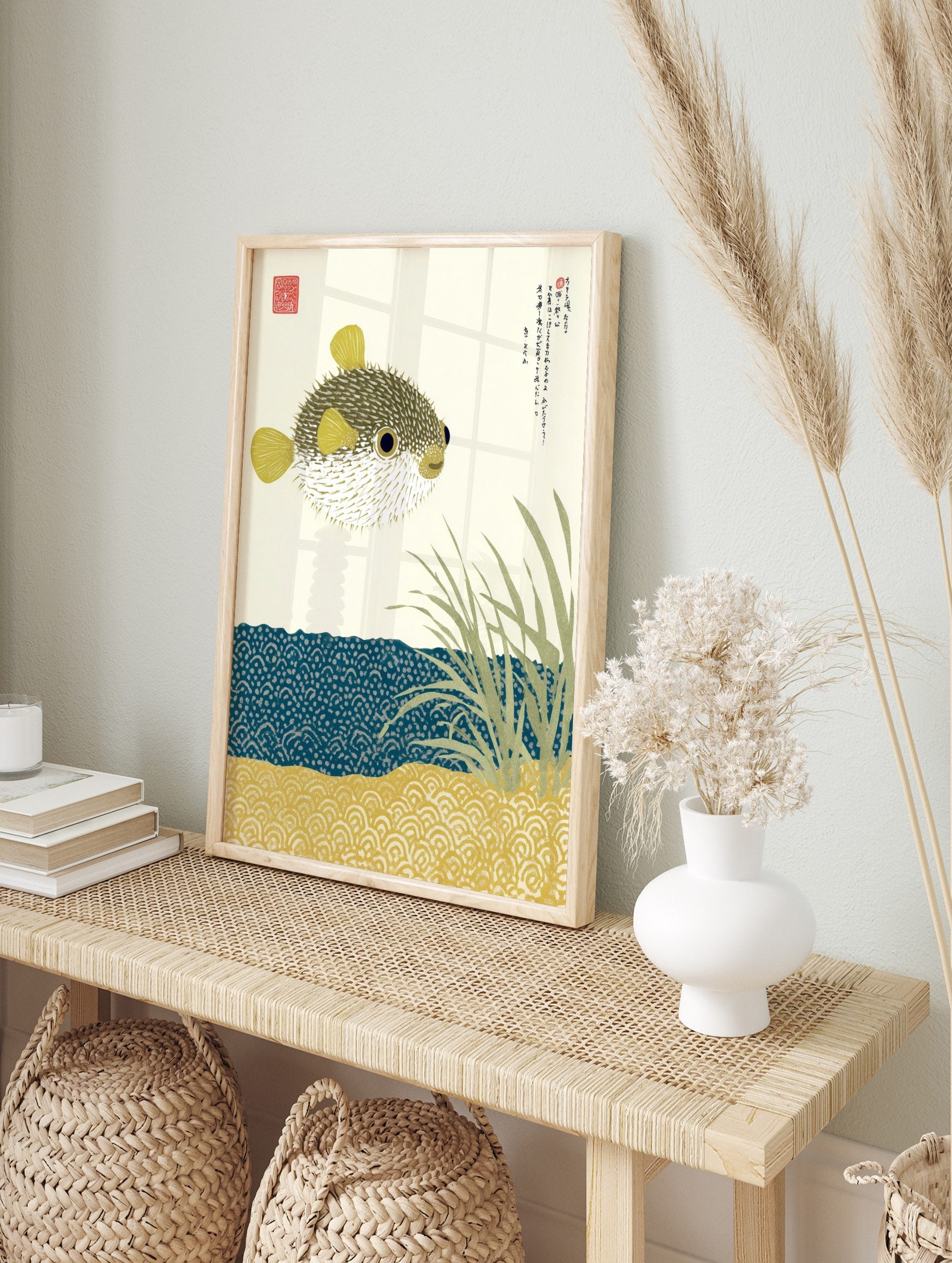 Illustrative pufferfish print with Japanese text, sea grass, and patterned blue water and sand, in an alternate framed mockup