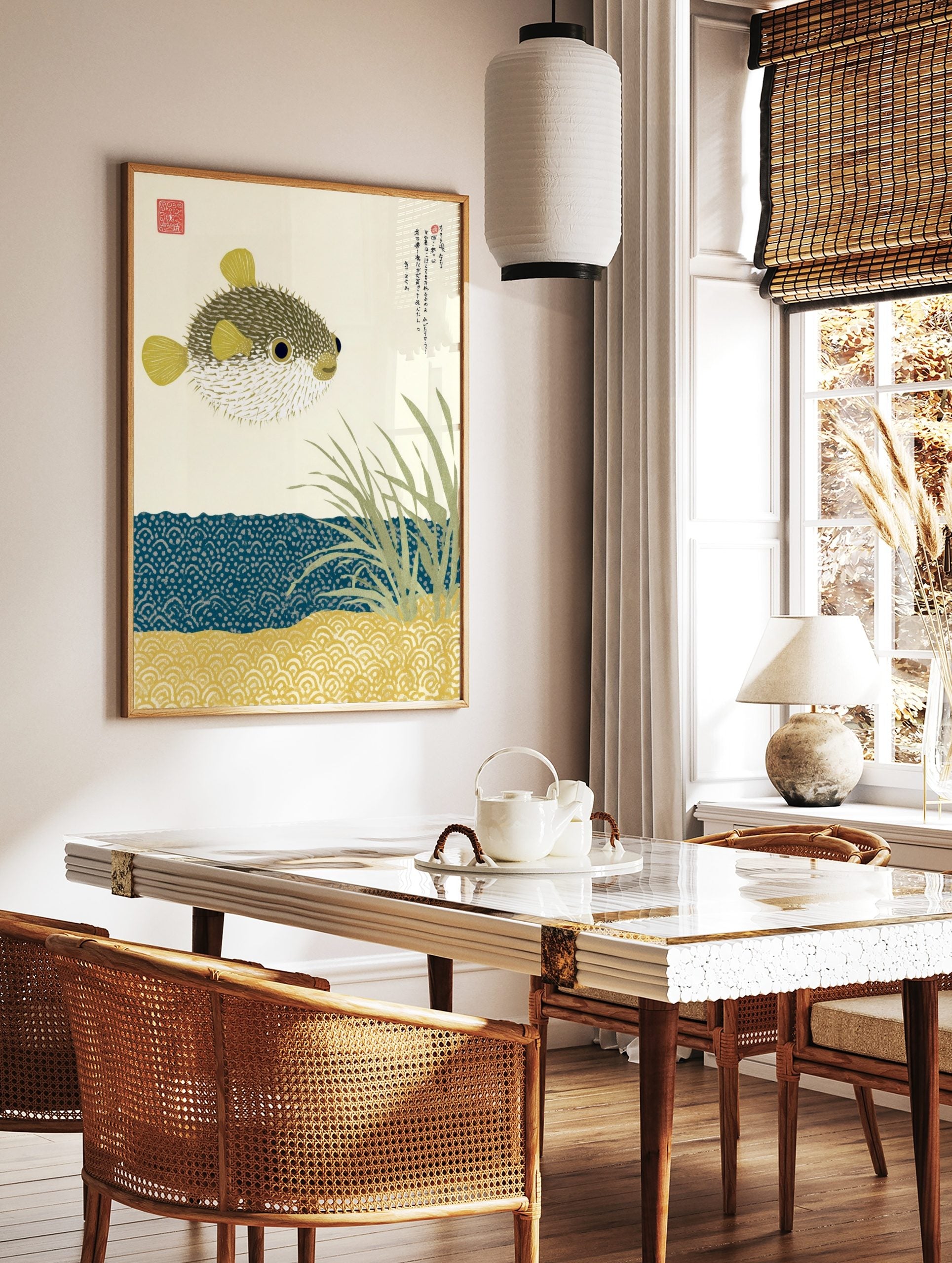 Illustrative pufferfish print with Japanese text, sea grass, and patterned blue water and sand, in a styled room mockup