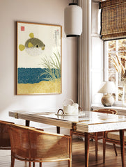 Illustrative pufferfish print with Japanese text, sea grass, and patterned blue water and sand, in a styled room mockup