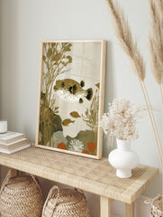 Illustrative pufferfish with brown spots and white underside, swimming amongst golden seaweed, in an alternate framed mockup