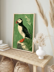 Illustrative puffin bird art print with black, white, red, and green tones, perched on a rock, in an alternate framed mockup