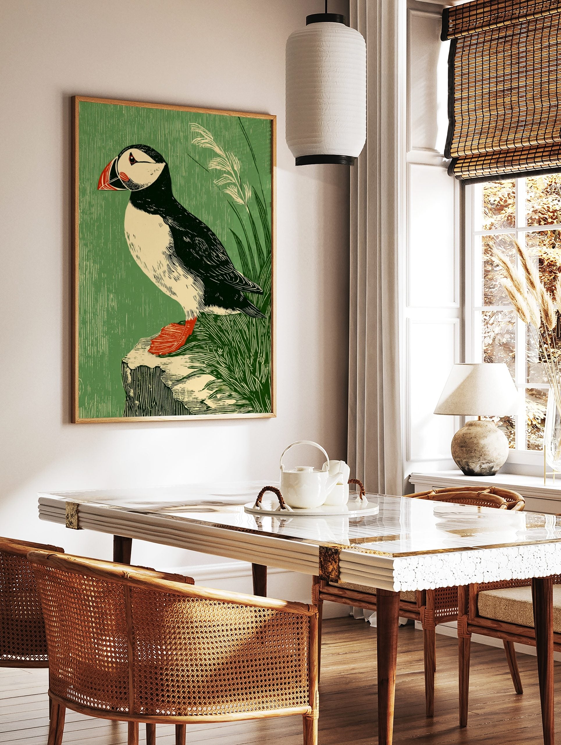 Illustrative puffin bird art print with black, white, red, and green tones, perched on a rock with, in a styled room mockup