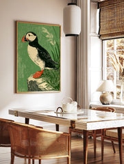 Illustrative puffin bird art print with black, white, red, and green tones, perched on a rock with, in a styled room mockup
