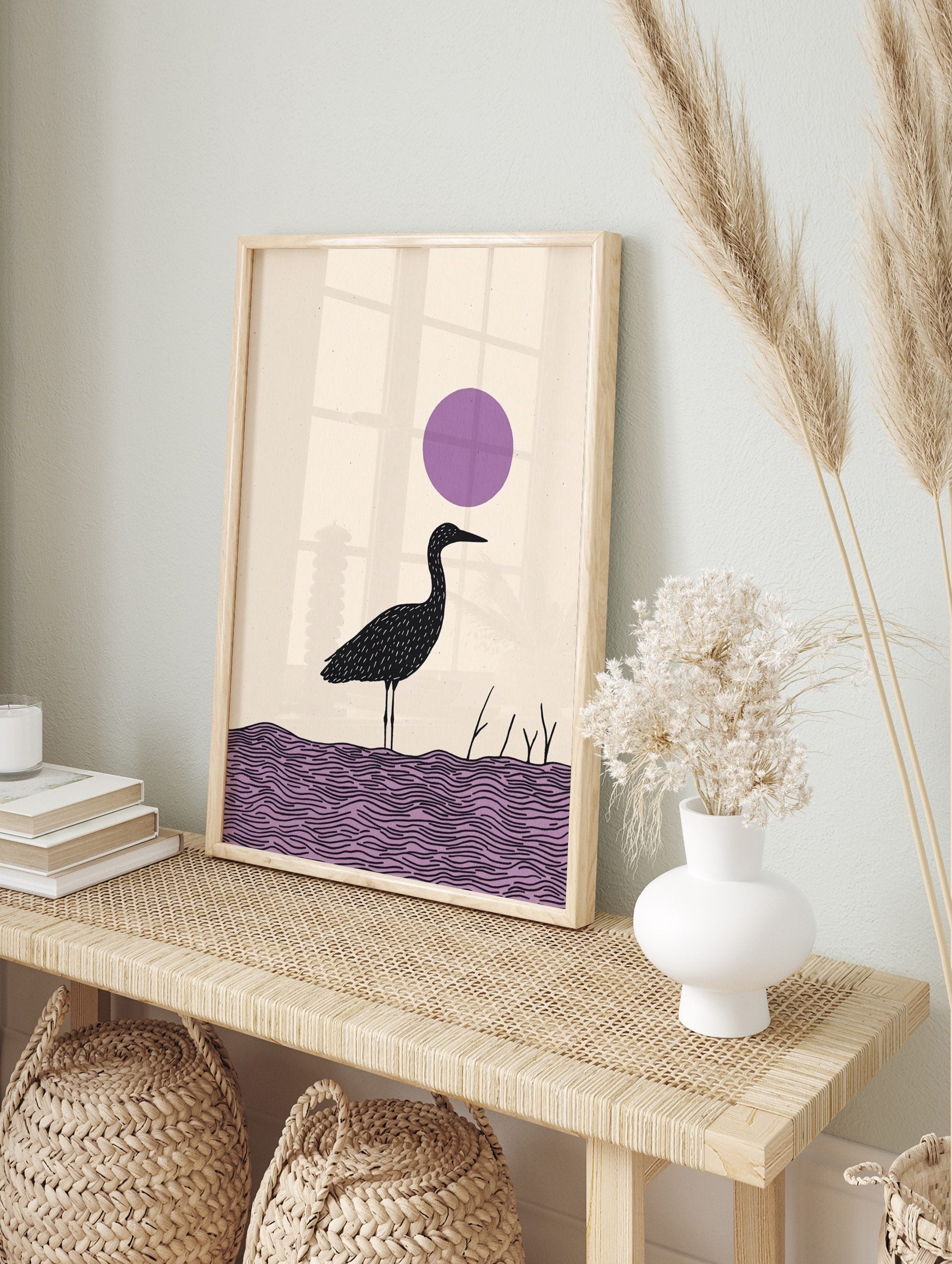 Minimalist black heron bird illustration standing in purple water with a large purple circle, in an alternate framed mockup