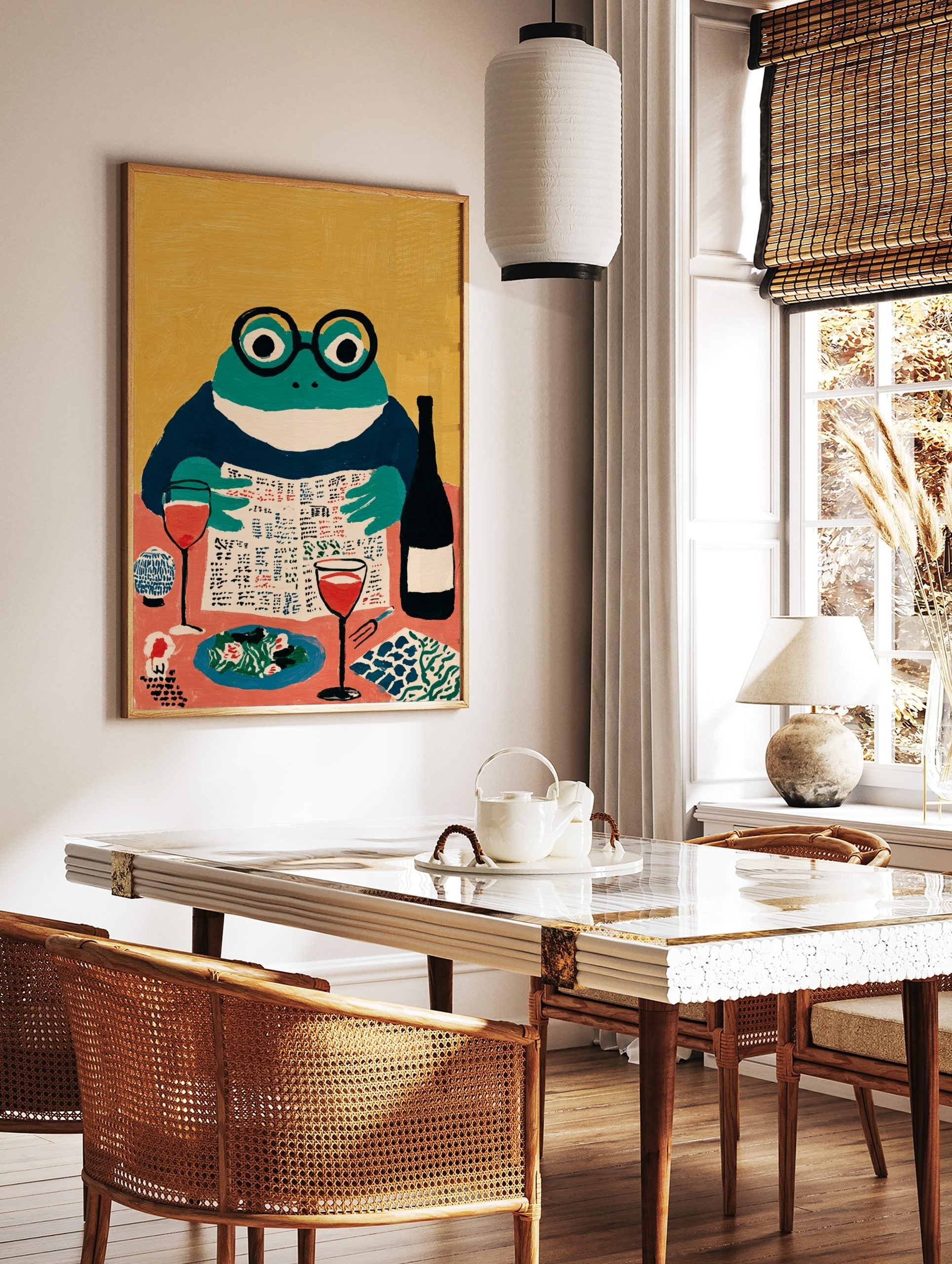Illustrative art print of a frog in glasses reading a newspaper at a dining table with wine and food, in a styled room mockup