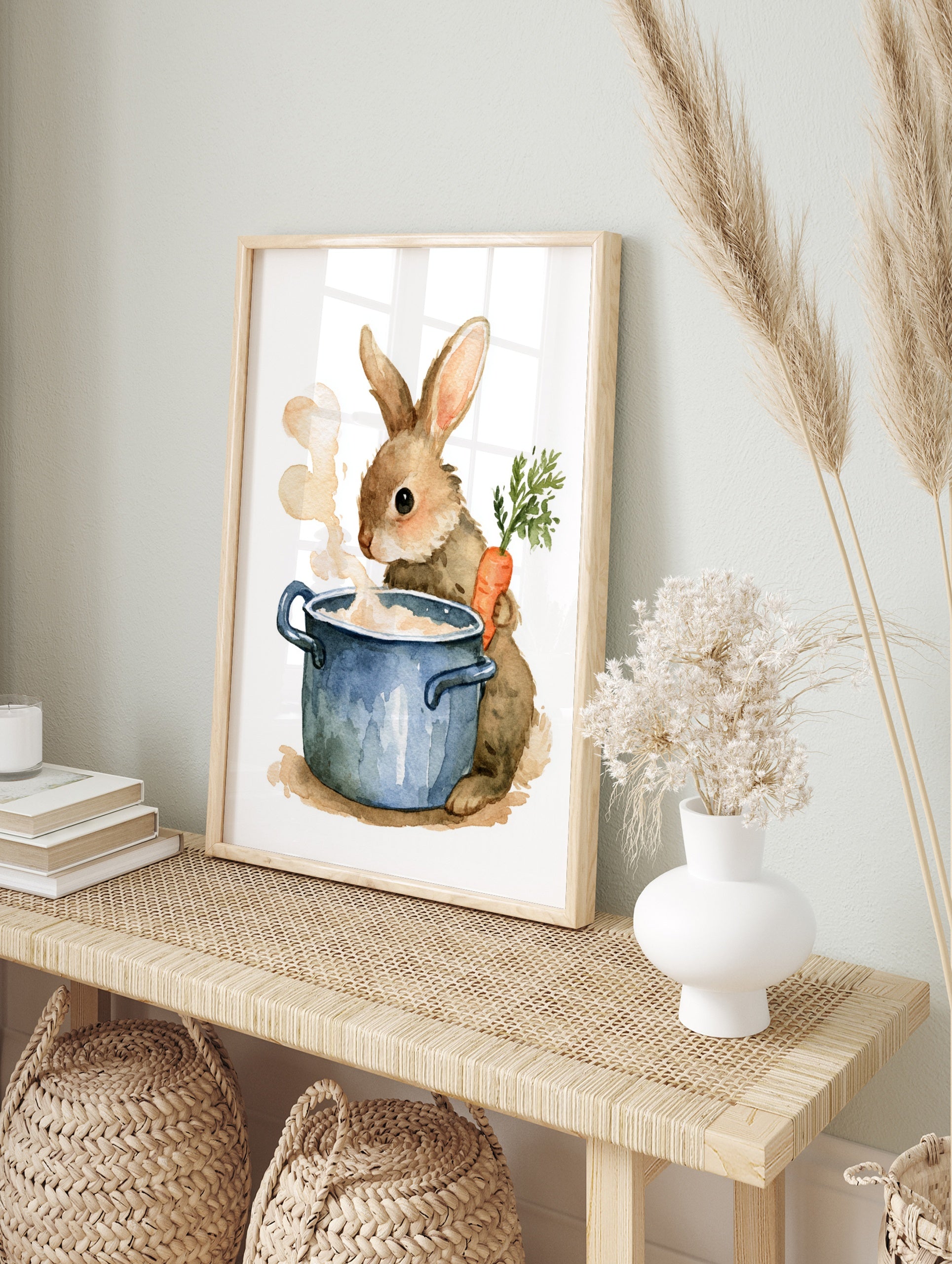 Watercolor illustration of a fluffy brown rabbit holding a carrot next to a steaming blue, in an alternate framed mockup