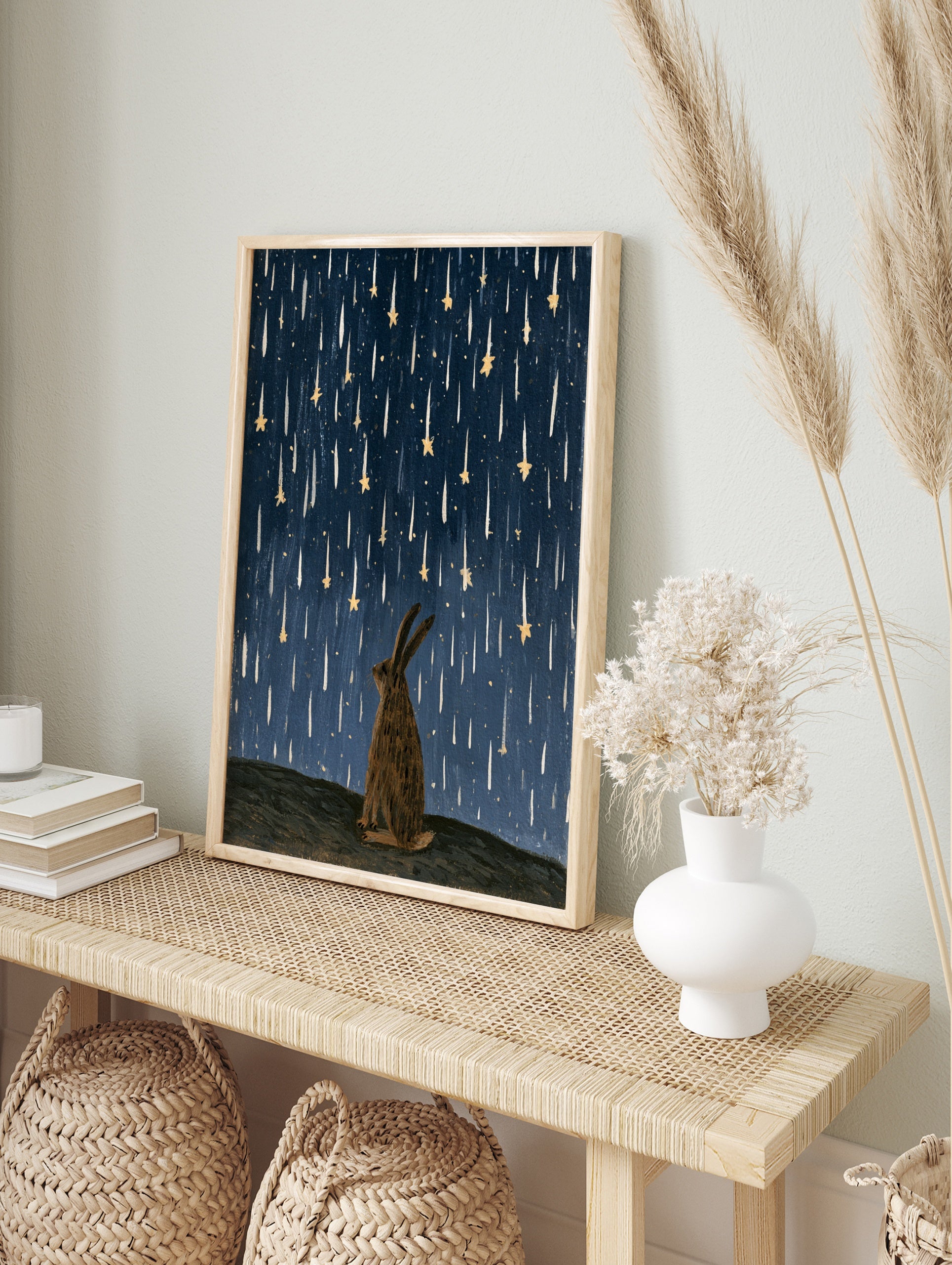 Illustrative rabbit silhouette gazing up at falling golden stars against a textured deep blue, in an alternate framed mockup