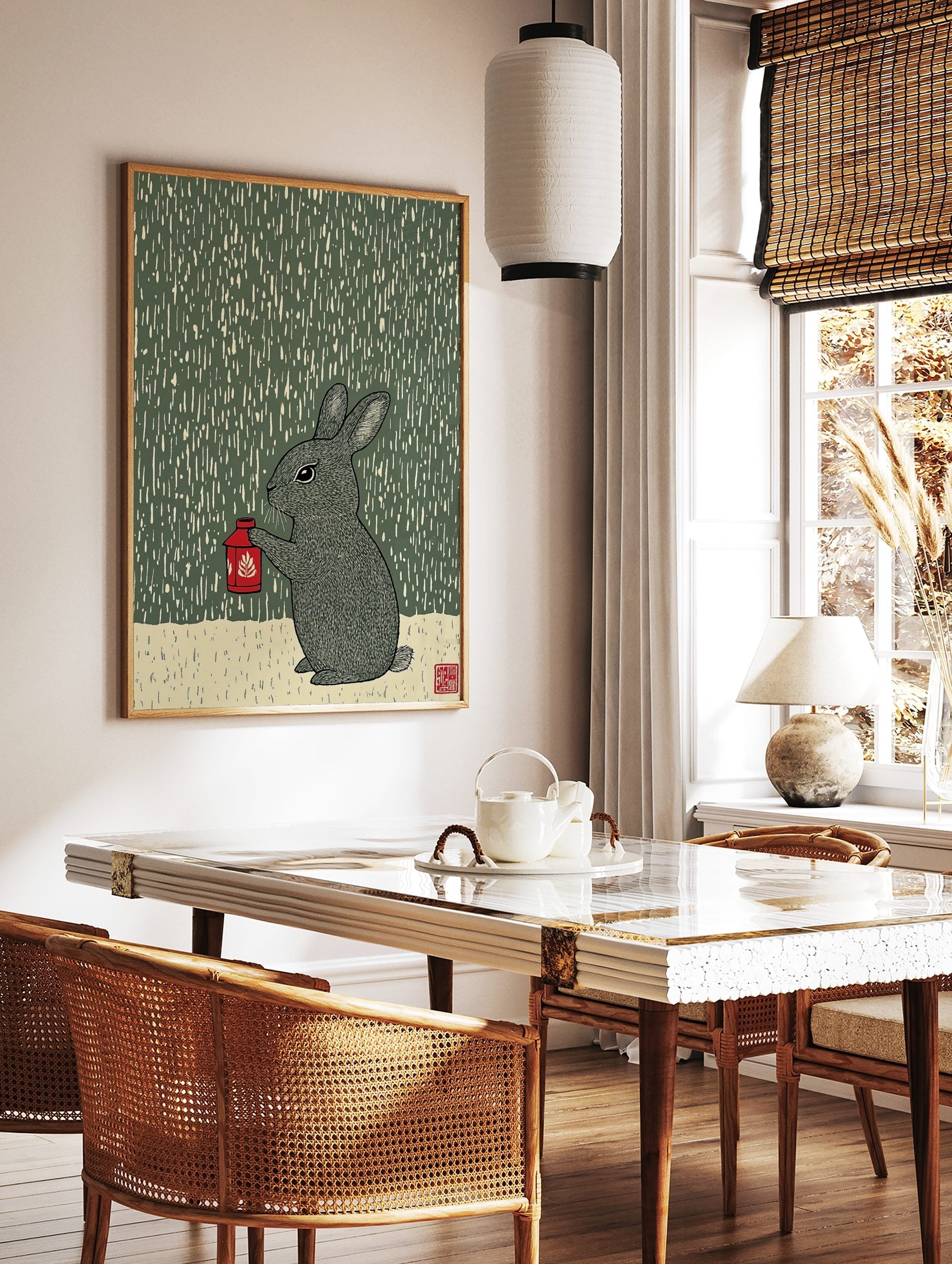 Illustrative woodcut style print of a grey rabbit holding a red lantern in the rain, dark green, in a styled room mockup