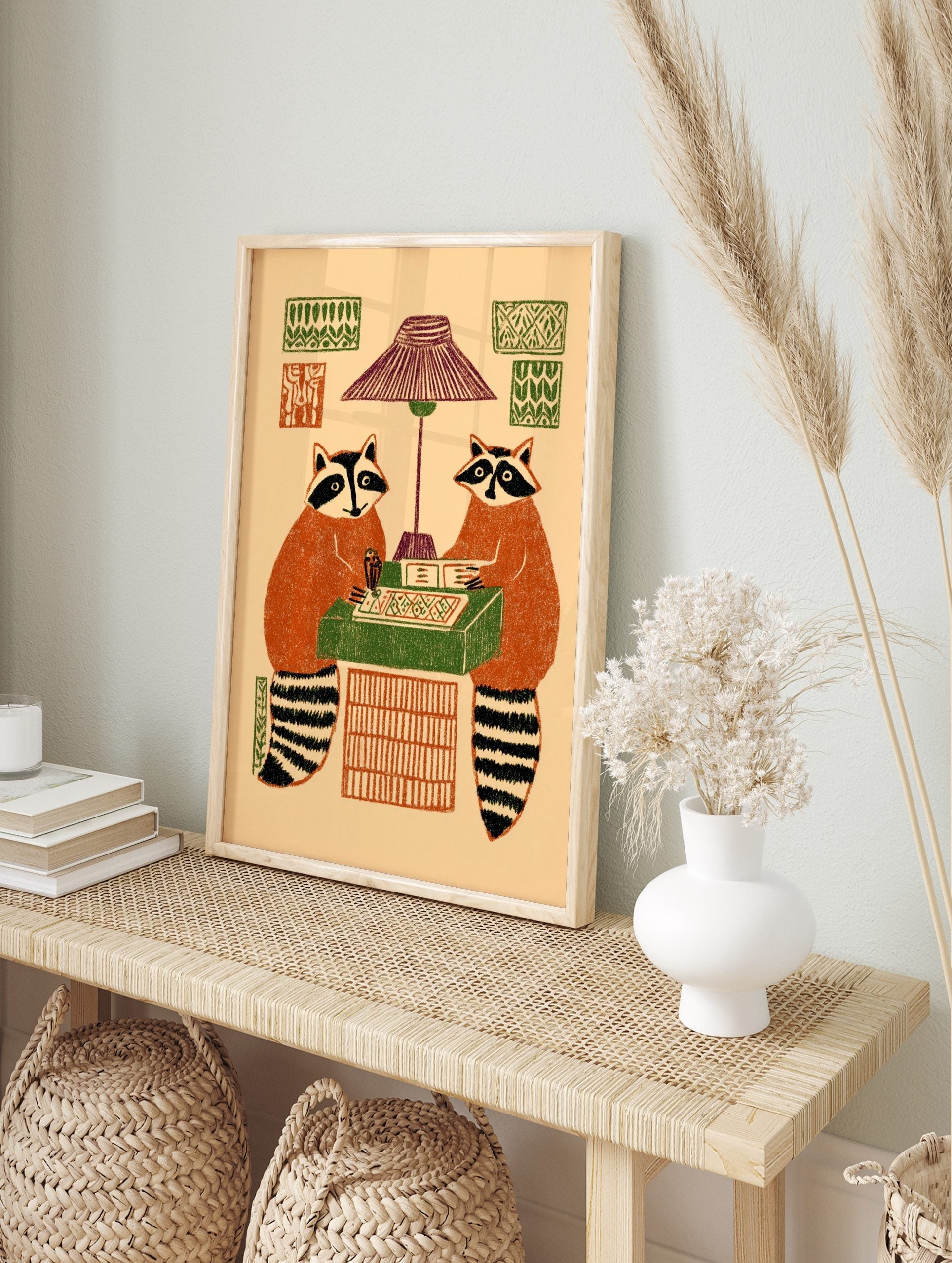 Illustrative print of two raccoons playing a board game under a lamp, with patterned wall, in an alternate framed mockup